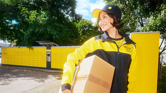Post Mitarbeiter*in mit Paket unter dem Arm